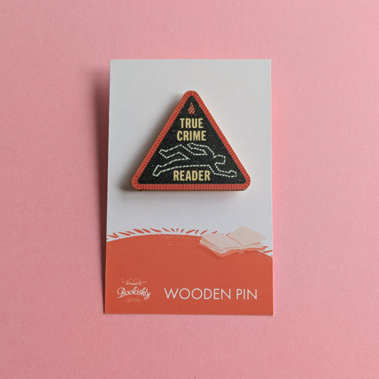 True Crime Reader wooden merit badge pin on backing card with pink background
