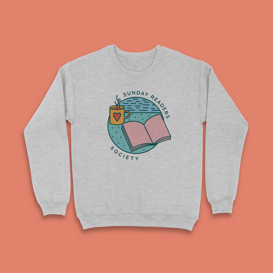 Grey sweatshirt with “Sunday Readers Society” design featuring open book and mug illustration.
