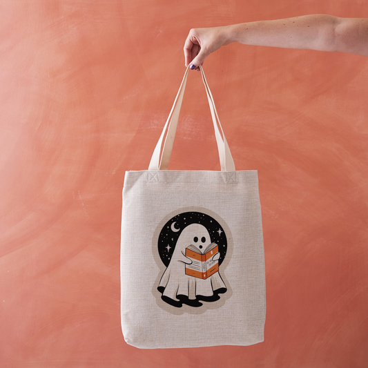 Linen-effect tote bag with ghost reading a book design.