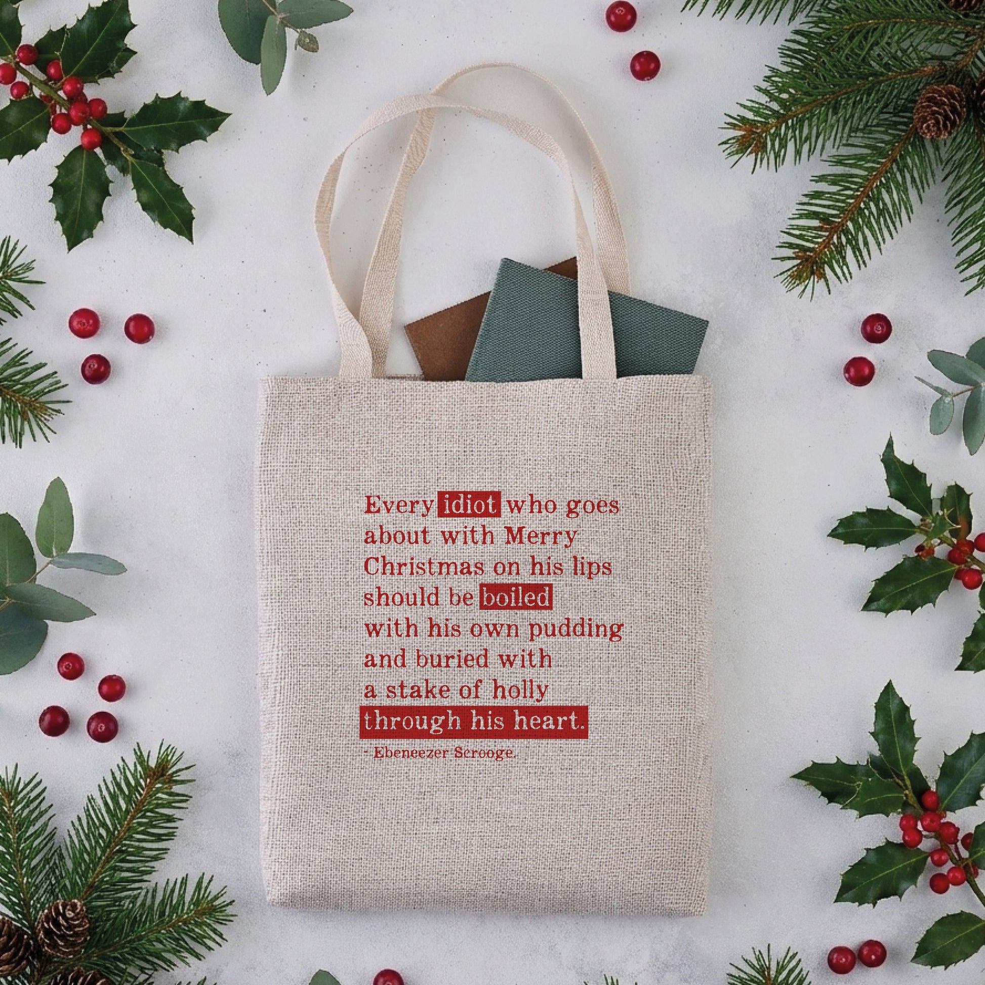 A natural coloured tote bag with a Christmas Carol quote in red text.