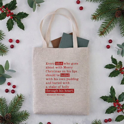 A natural coloured tote bag with a Christmas Carol quote in red text.
