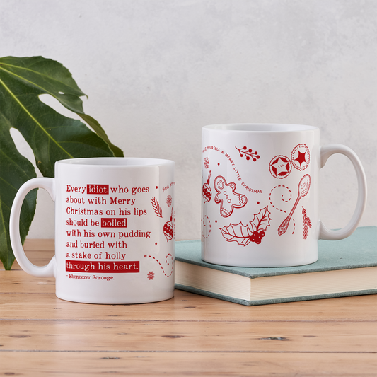 A white mug with red text featuring a quote from A Christmas Carol with small Christmas designs.