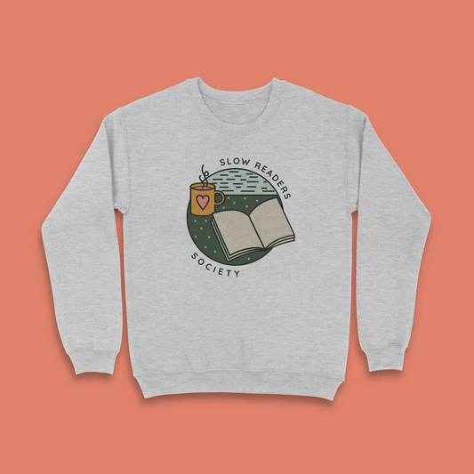 Grey sweatshirt with “Slow Readers Society” design featuring open book and mug illustration.