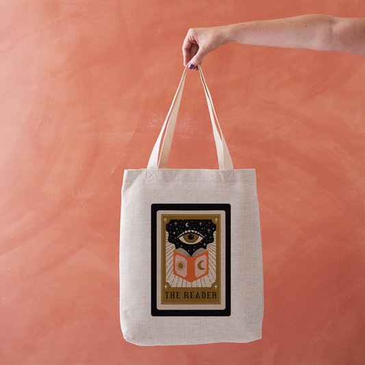 Linen-effect tote bag with tarot card design reading “The Reader.”